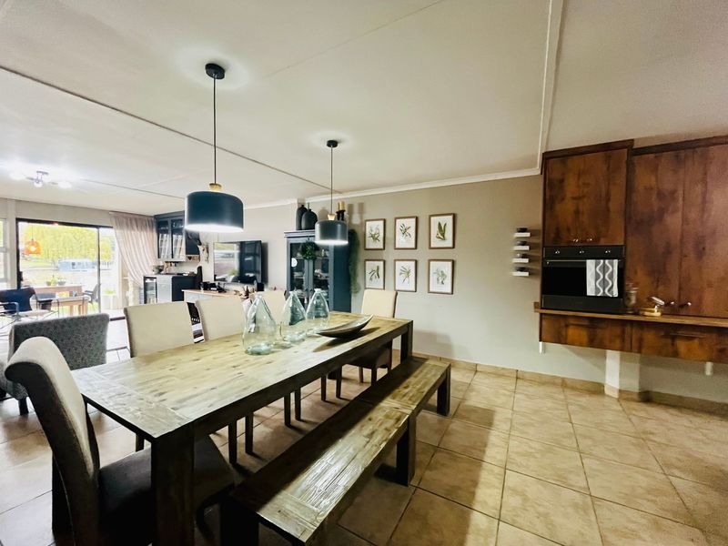 Spacious open-plan dining and kitchen area featuring tiled floors, built-in oven, wooden cabinetry, and direct access to an outdoor patio through sliding glass doors.