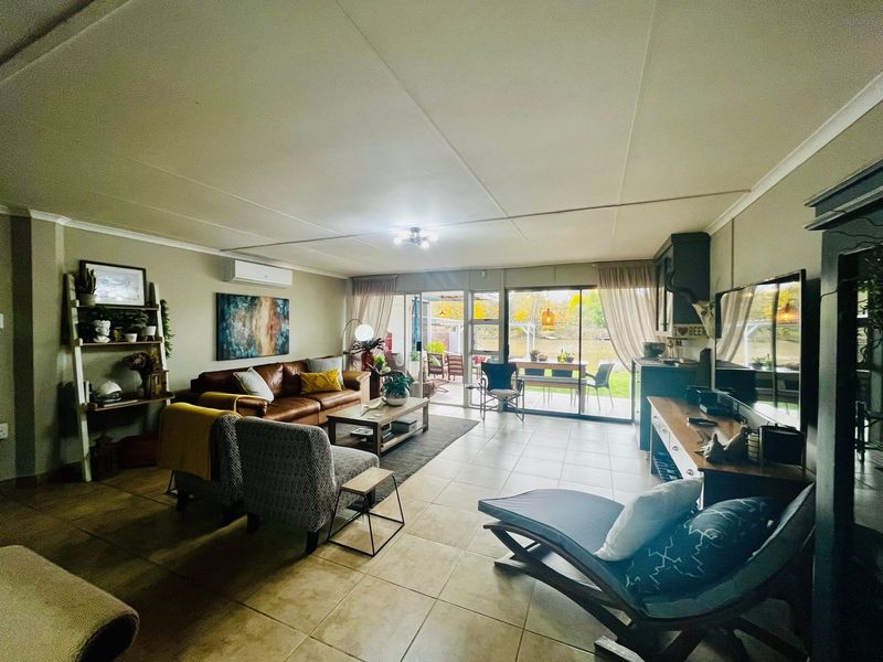 Spacious open-plan living area featuring tiled flooring, split-system air conditioning, and large sliding glass doors providing access to the outdoor patio.