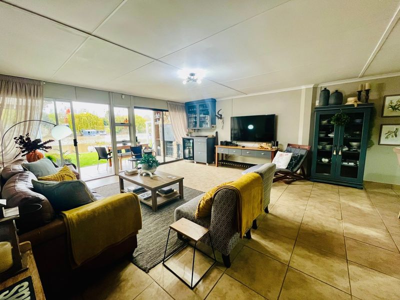 Spacious living room featuring tiled flooring, built-in cabinetry, and large sliding glass doors providing natural light and access to the outdoor patio area.