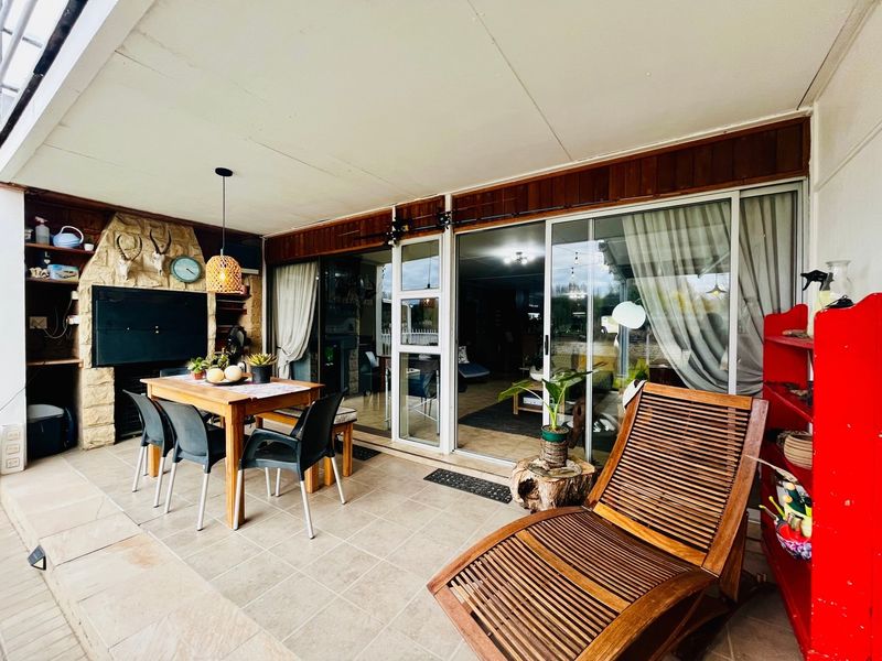 Covered patio area featuring a built-in braai with stone cladding, tiled flooring, and sliding glass doors providing access to the interior living space.