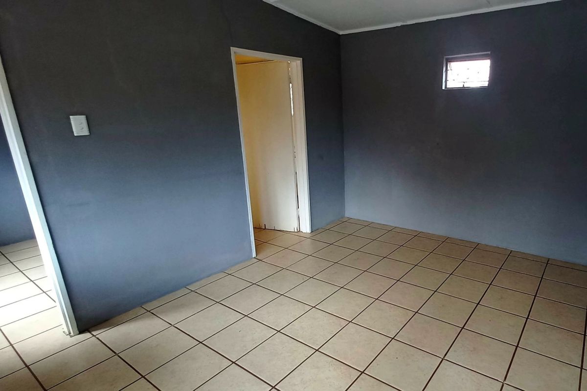 An empty bedroom featuring dark grey painted walls and neutral ceramic floor tiles, providing a blank canvas for potential interior design updates.