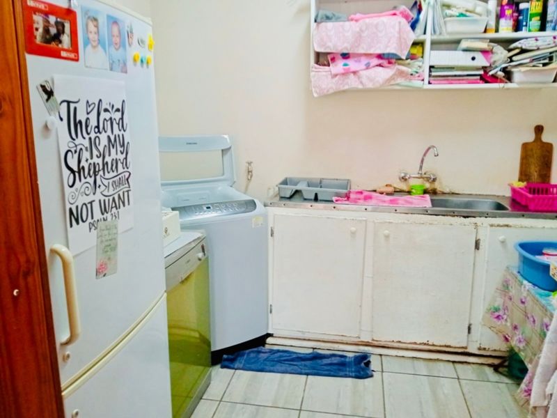 A functional laundry area featuring built-in cabinetry, a stainless steel sink, and tiled flooring, providing essential utility space for the home.