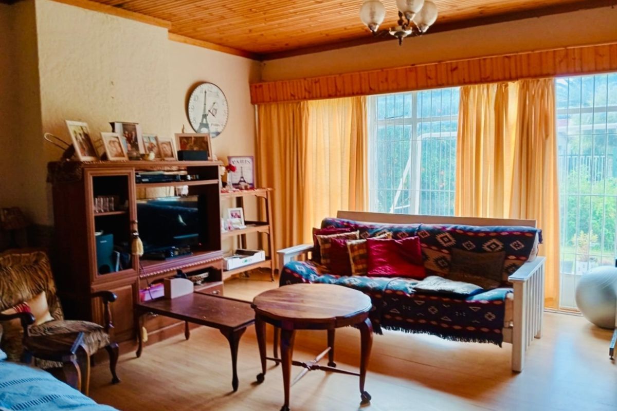 A living room featuring a timber-clad ceiling, laminate flooring, and large windows that provide natural light.
