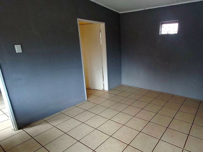 An empty bedroom featuring dark grey painted walls and neutral ceramic floor tiles, providing a blank canvas for potential interior design updates.
