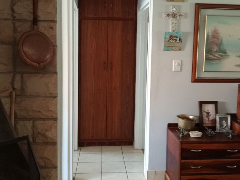 A hallway featuring tiled flooring, a stone feature wall, and built-in wooden storage cupboards.