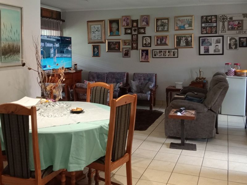 Open plan living and dining area featuring tiled flooring and an integrated kitchen space with a breakfast bar.