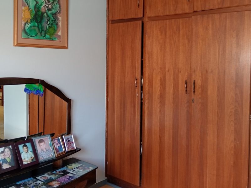 A bedroom featuring floor-to-ceiling built-in wooden wardrobes with a classic finish.