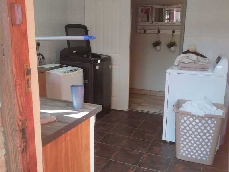 A functional laundry room featuring tiled flooring, wall tiling, and built-in cabinetry for storage and utility use.