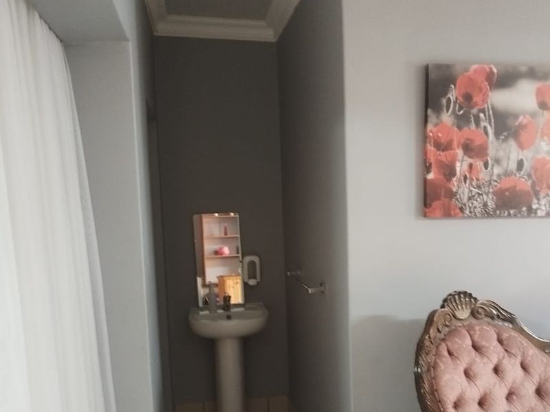 A bedroom featuring a corner pedestal washbasin and a wall-mounted towel rail, finished with crown molding.