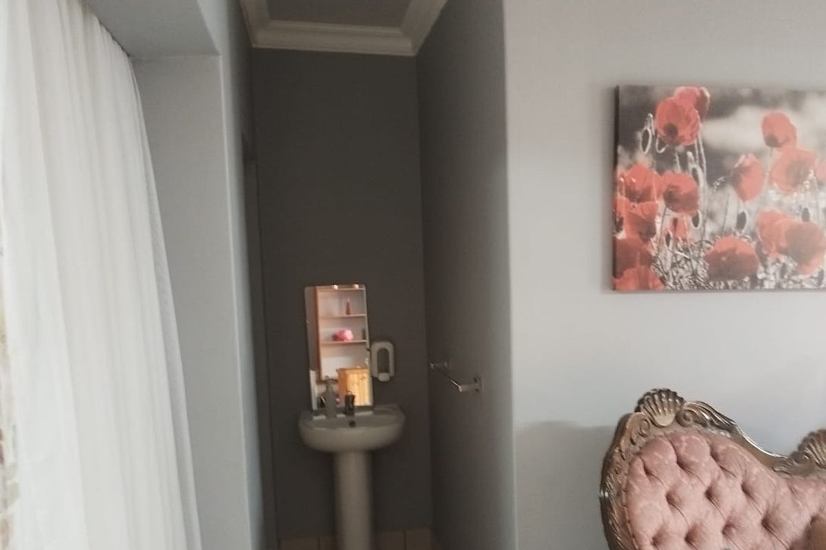 A bedroom featuring a corner pedestal washbasin and a wall-mounted towel rail, finished with crown molding.