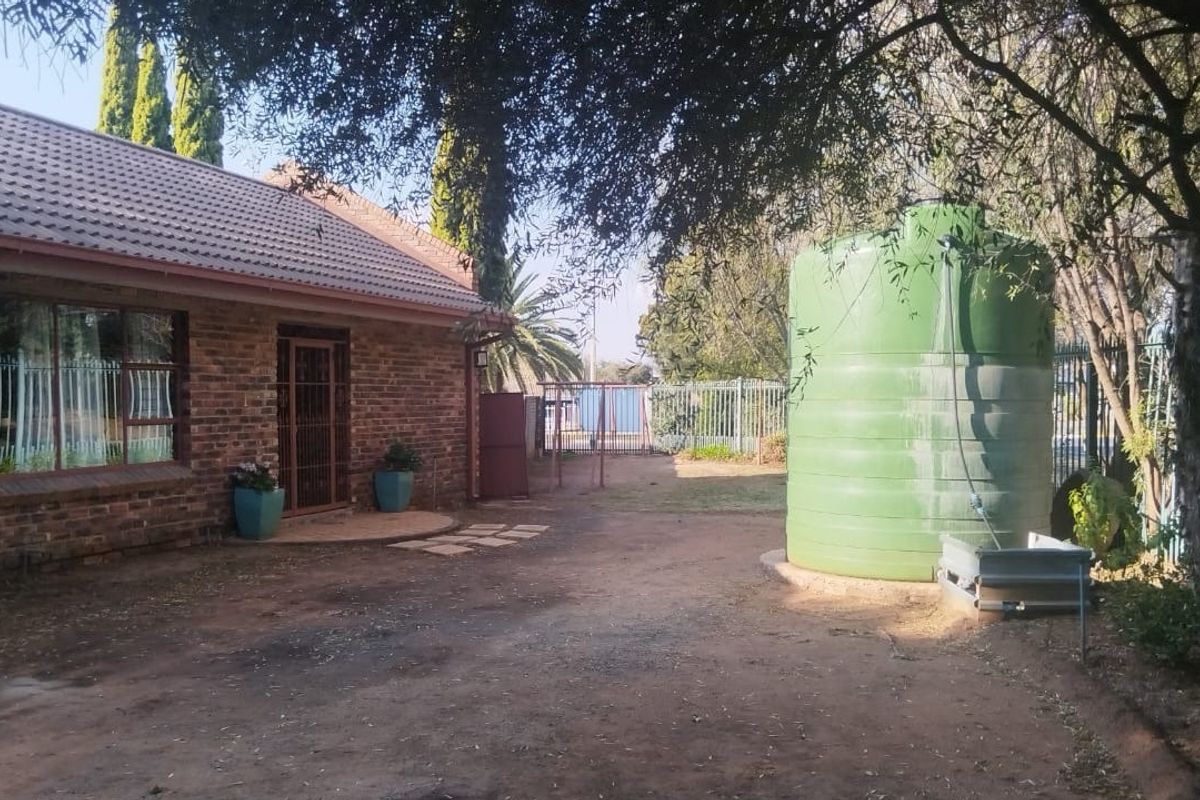 Rear exterior view of the guest house featuring a face brick facade, tiled roof, and a large water storage tank on the property grounds.