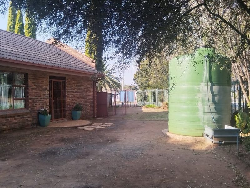Rear exterior view of the guest house featuring a face brick facade, tiled roof, and a large water storage tank on the property grounds.