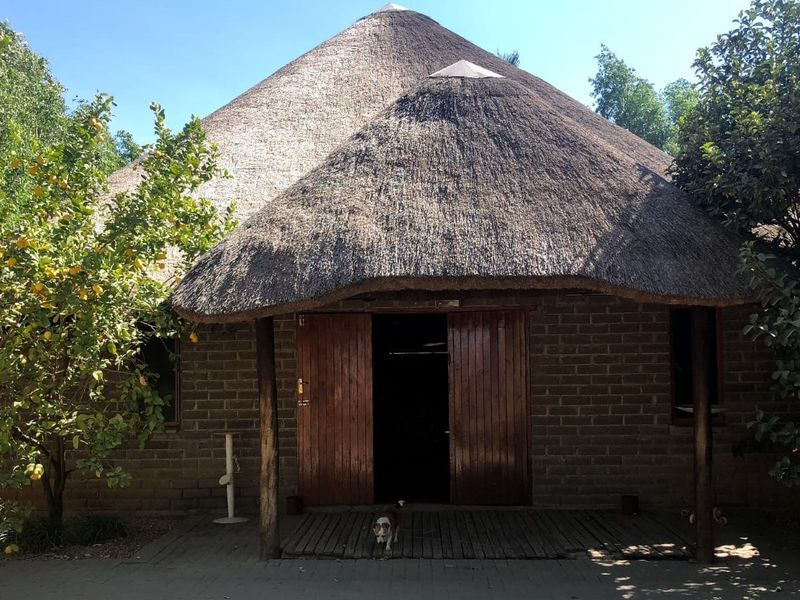 A charming lodge-style building featuring a traditional thatched roof, exposed brick facade, and a welcoming wooden deck entrance.