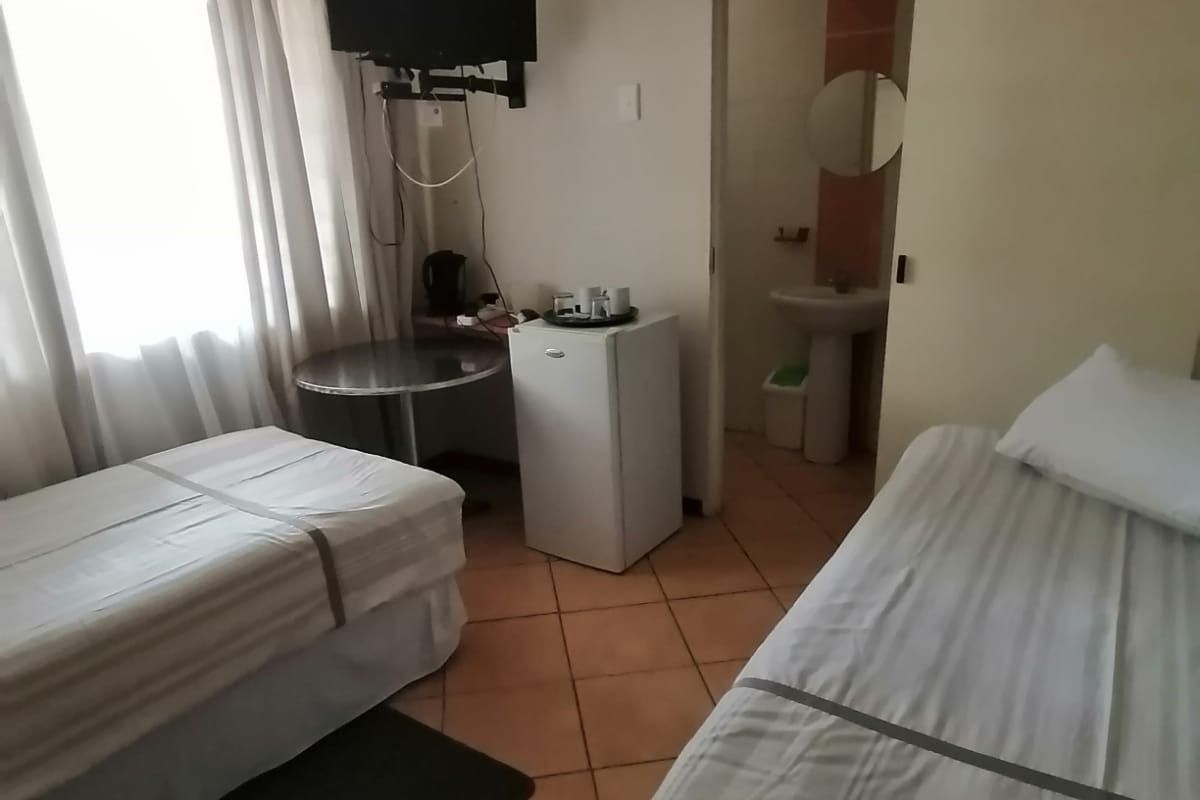 A functional lodge bedroom featuring tiled flooring and an en-suite bathroom with a pedestal basin.