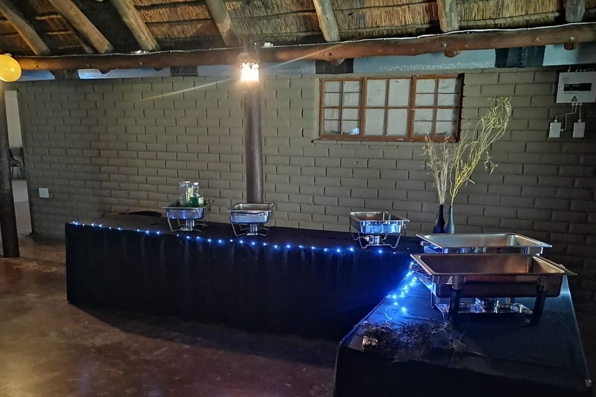 Rustic lodge interior featuring exposed brick walls, timber support beams, and a traditional thatched roof structure.