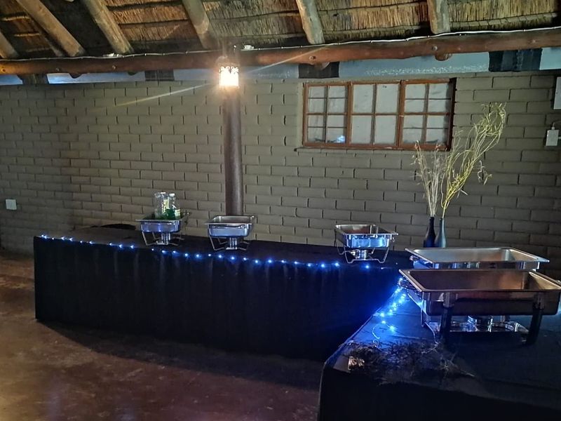 Rustic lodge interior featuring exposed brick walls, timber support beams, and a traditional thatched roof structure.