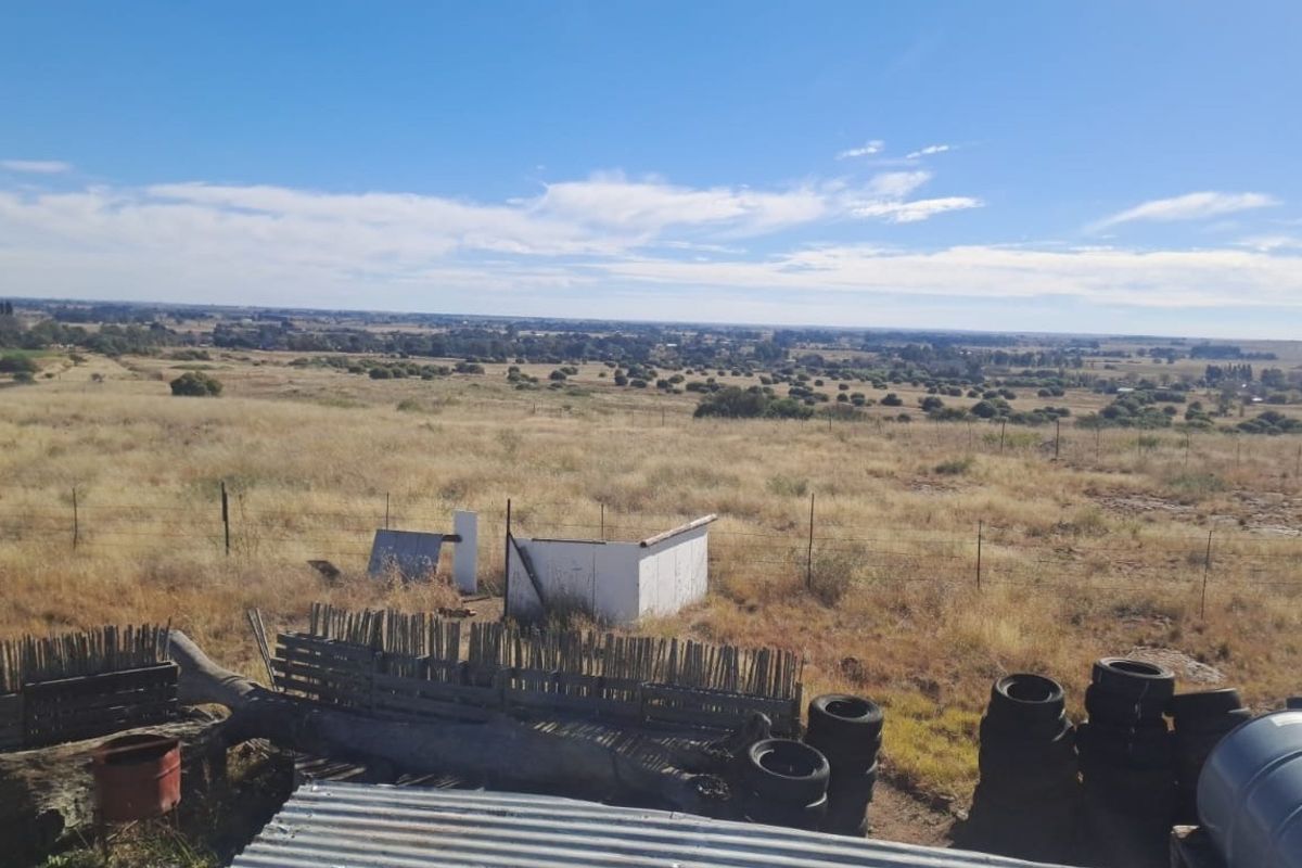Expansive rural landscape view overlooking open farmland with wire fencing and distant horizon.