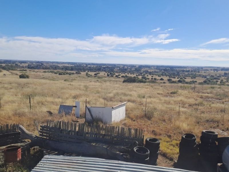 Expansive rural landscape view overlooking open farmland with wire fencing and distant horizon.