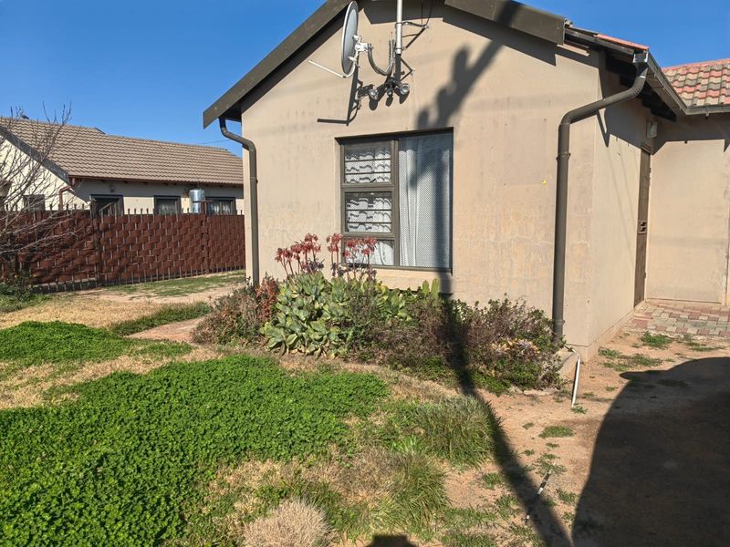 Rear exterior view of the property showing the building facade, window, and surrounding garden area.