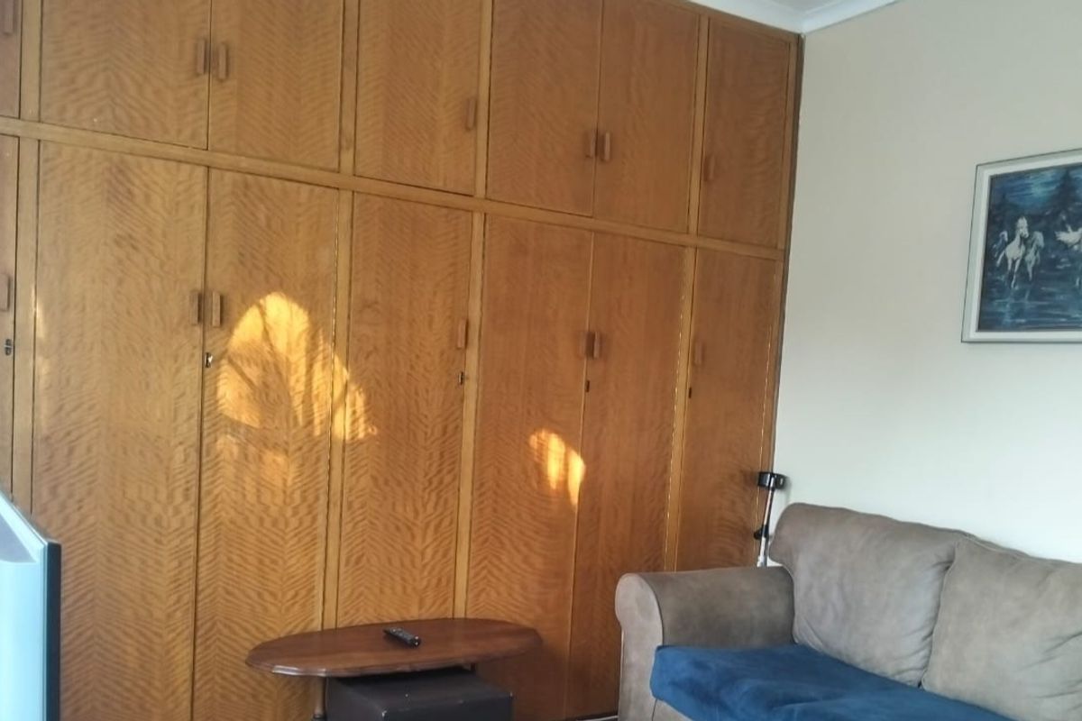 A bedroom featuring extensive floor-to-ceiling built-in wooden cabinetry providing ample storage space.