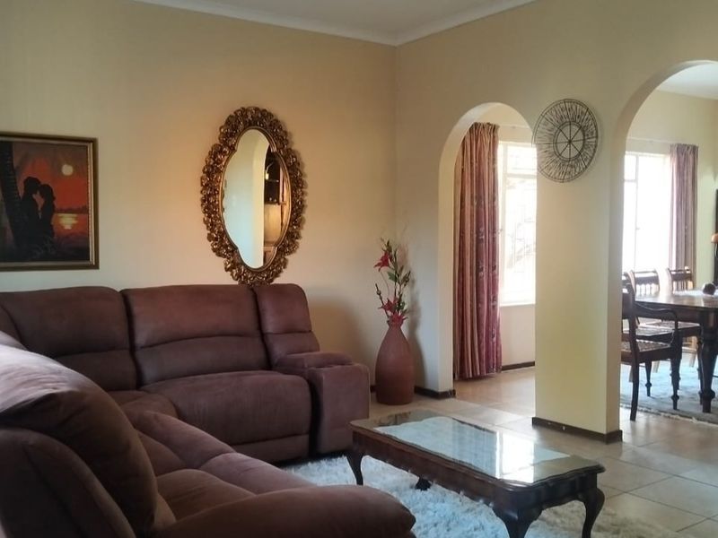 Open plan living and dining area featuring arched architectural transitions and neutral tiled flooring.