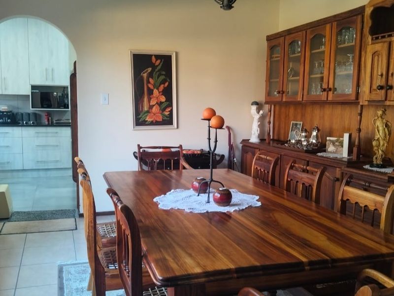 A traditional dining room featuring tiled flooring and an arched entryway leading into a modern kitchen area.