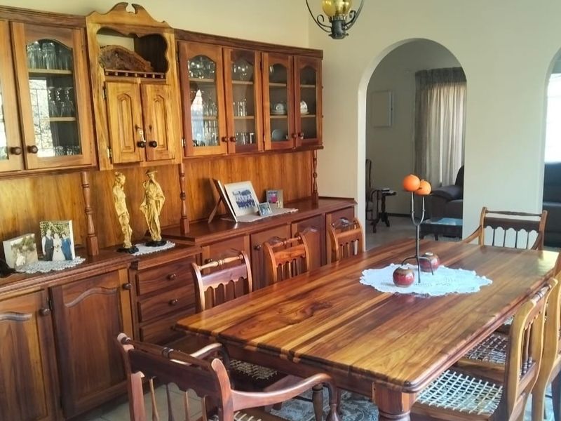 A traditional dining room featuring extensive built-in wooden cabinetry, tiled flooring, and an arched entryway leading to an adjacent living space.