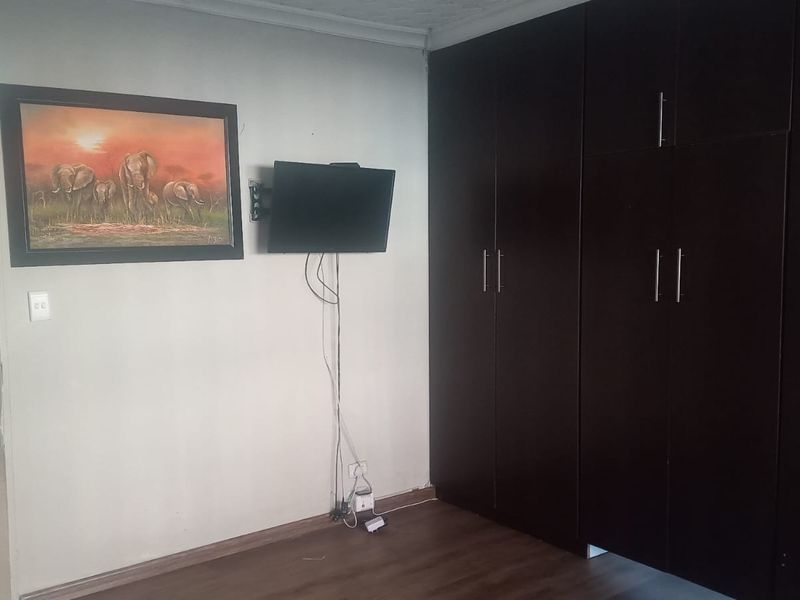 A bedroom featuring dark wood-finish built-in cupboards and laminate flooring, providing functional storage and a neutral base for interior design.