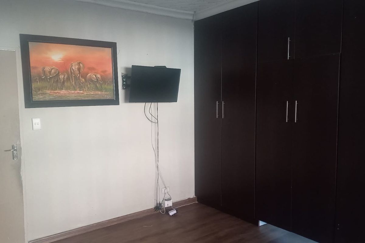 A bedroom featuring dark wood-finish built-in cupboards and laminate flooring, providing functional storage and a neutral base for interior design.