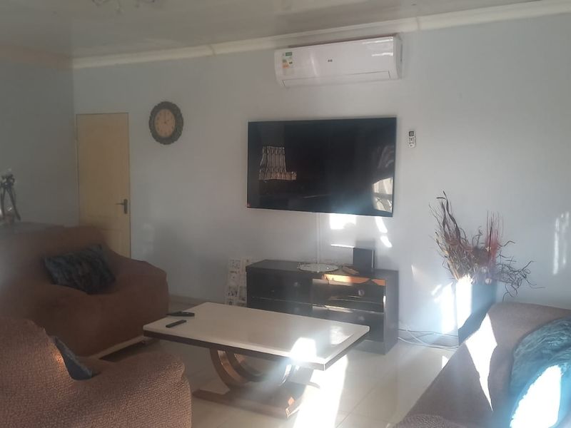 A living room featuring tiled flooring and a wall-mounted air conditioning unit.