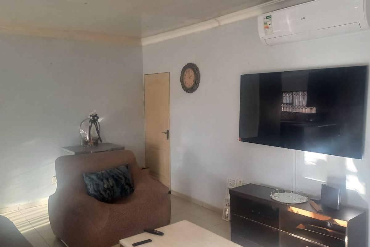 A living room featuring tiled flooring, coving, and a wall-mounted split-system air conditioner.