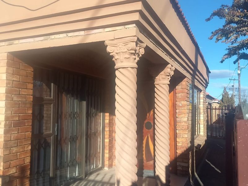 Front facade of the house featuring face brick construction, decorative spiral columns, and a secure entrance with a sliding door.