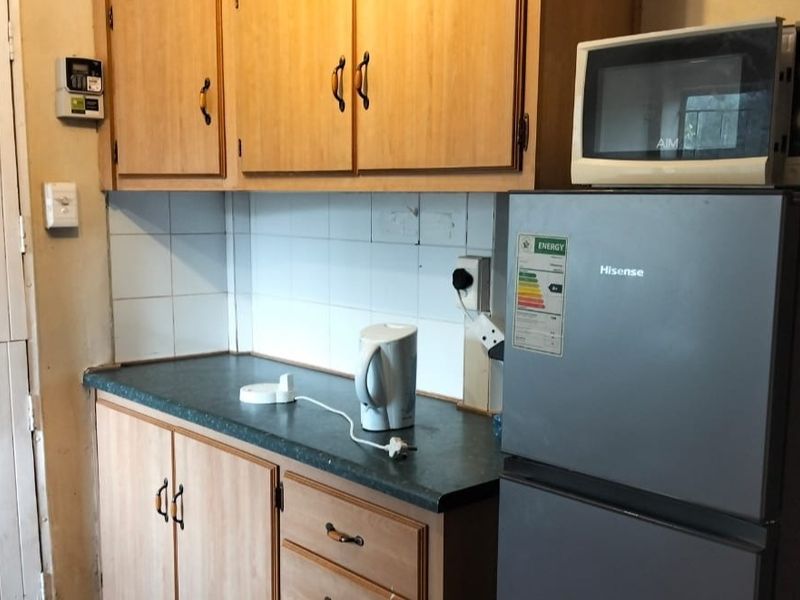 A dated kitchen featuring laminate cabinetry, a dark countertop, and a tiled backsplash, offering potential for a modern renovation.