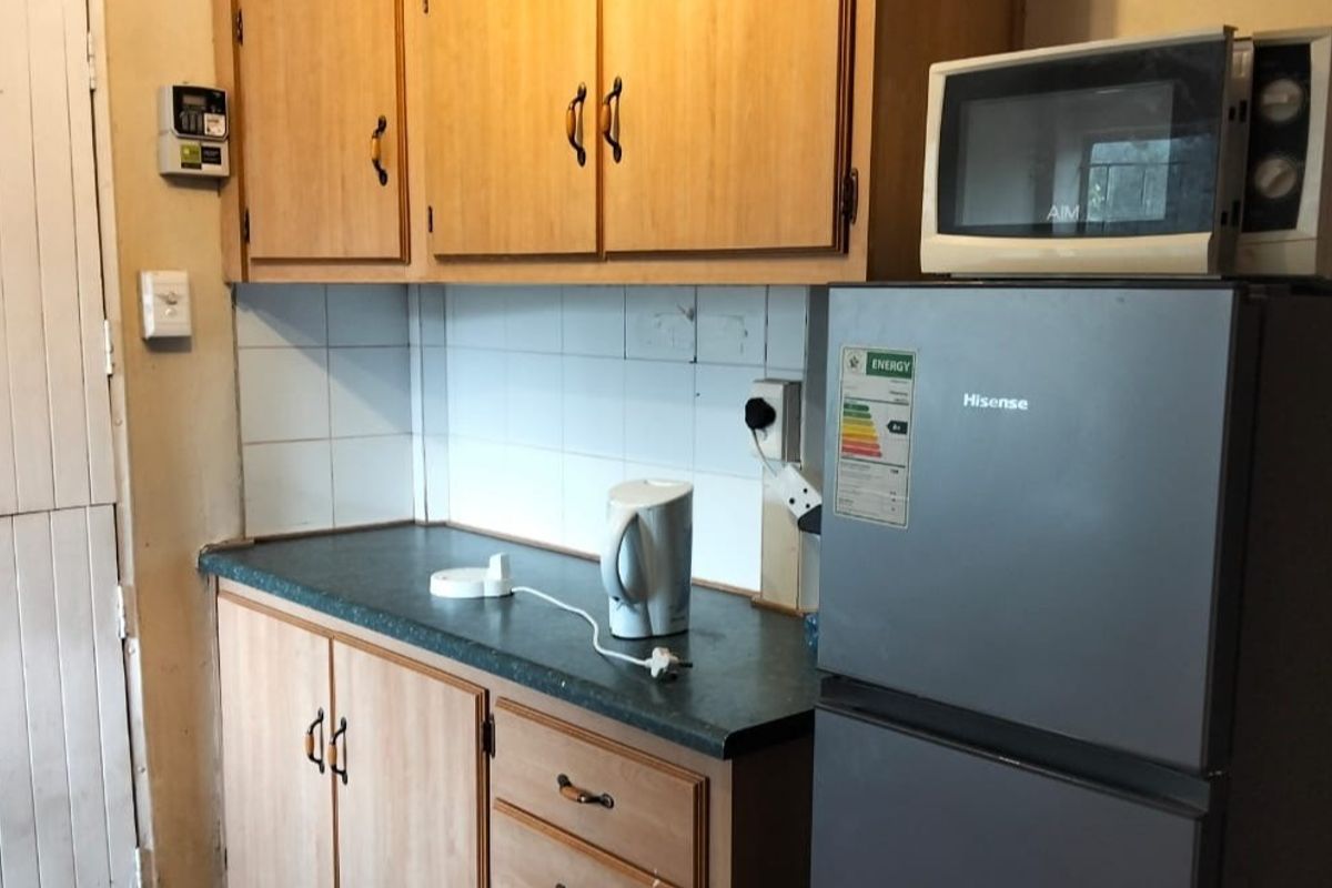 A dated kitchen featuring laminate cabinetry, a dark countertop, and a tiled backsplash, offering potential for a modern renovation.