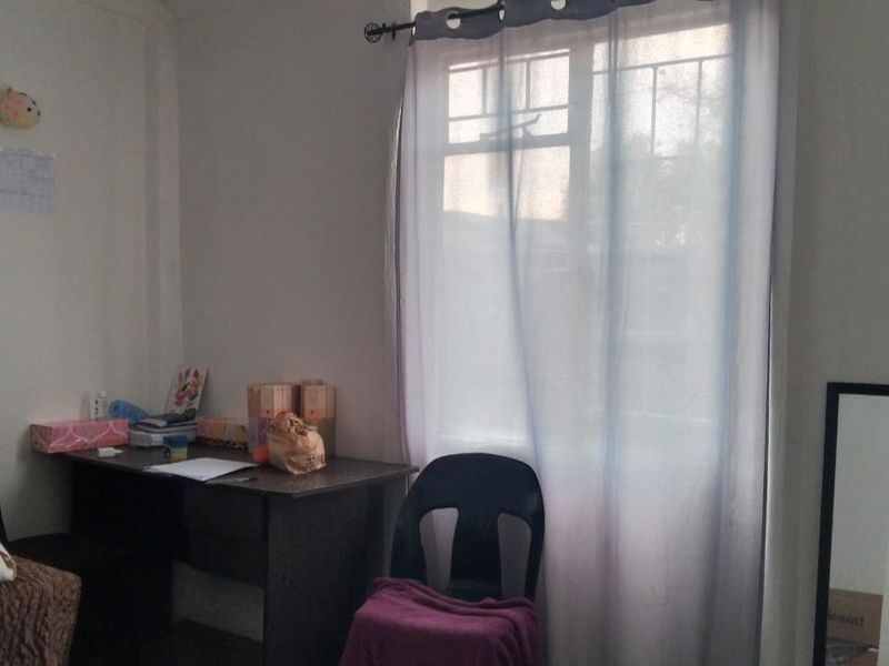 A simple bedroom featuring a window with a curtain rod, providing natural light and a functional space for rest or study.