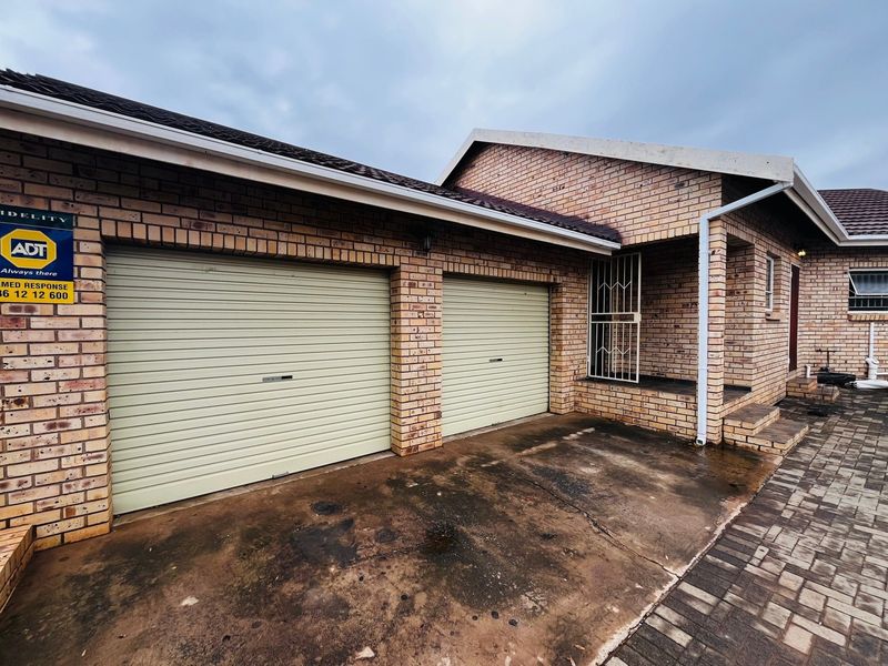 Exterior view of a double garage featuring roller doors, face brick construction, and a paved driveway area.