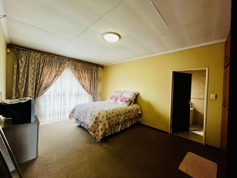 Spacious bedroom featuring built-in cupboards, carpeted flooring, and direct access to an en-suite bathroom.