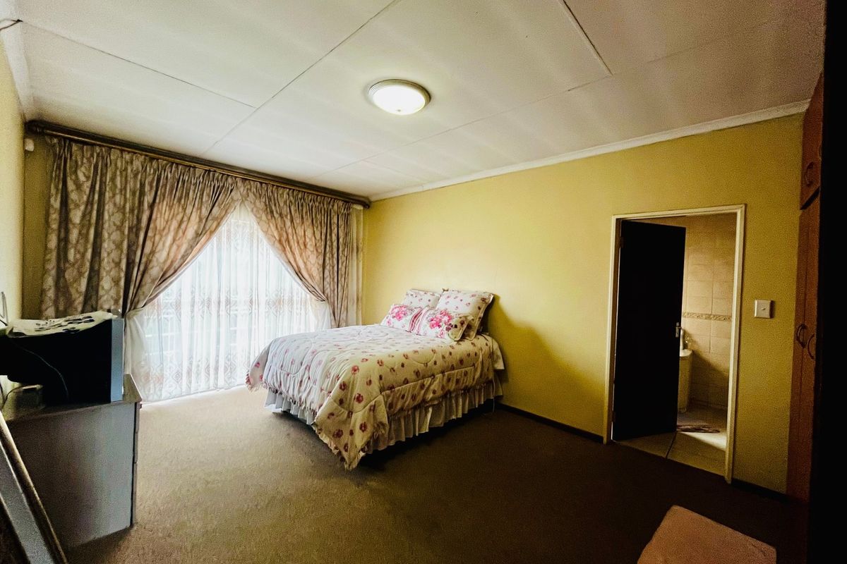 Spacious bedroom featuring built-in cupboards, carpeted flooring, and direct access to an en-suite bathroom.
