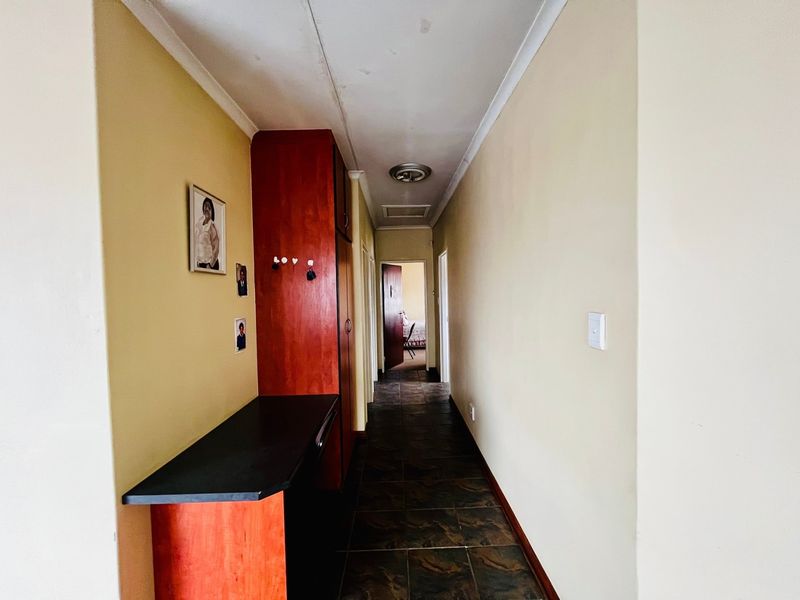 A functional hallway featuring tiled flooring, built-in cabinetry, and access to adjacent rooms.
