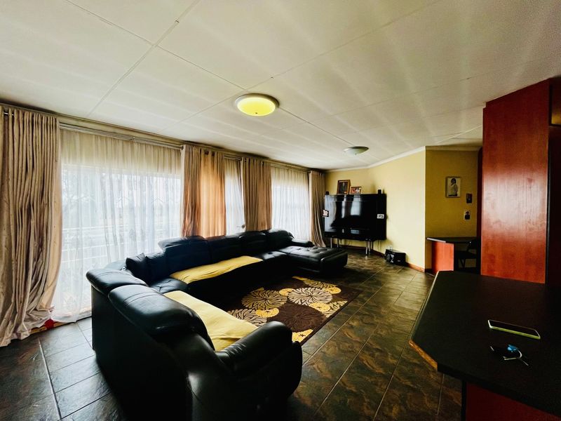Spacious living area featuring tiled flooring and large sliding glass doors that provide ample natural light.