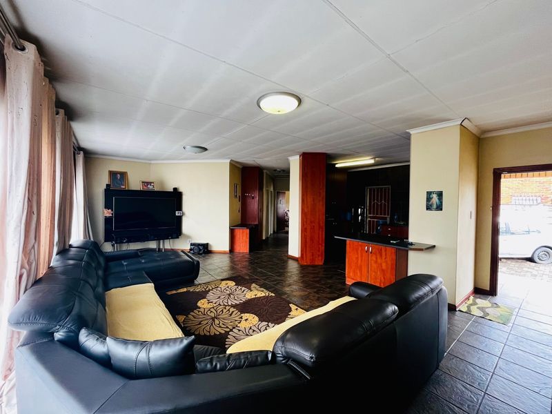 Open plan living area featuring tiled flooring, built-in cabinetry, and a breakfast counter, providing a functional layout connecting the living space and kitchen area.