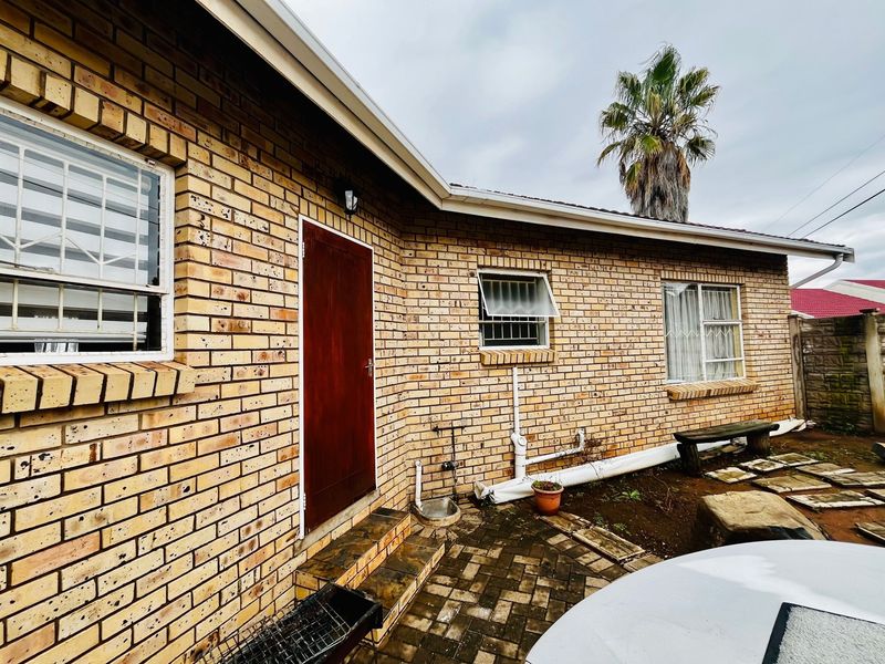 Rear exterior view of the duet property featuring face brick construction, a paved patio area, and security-fitted windows.