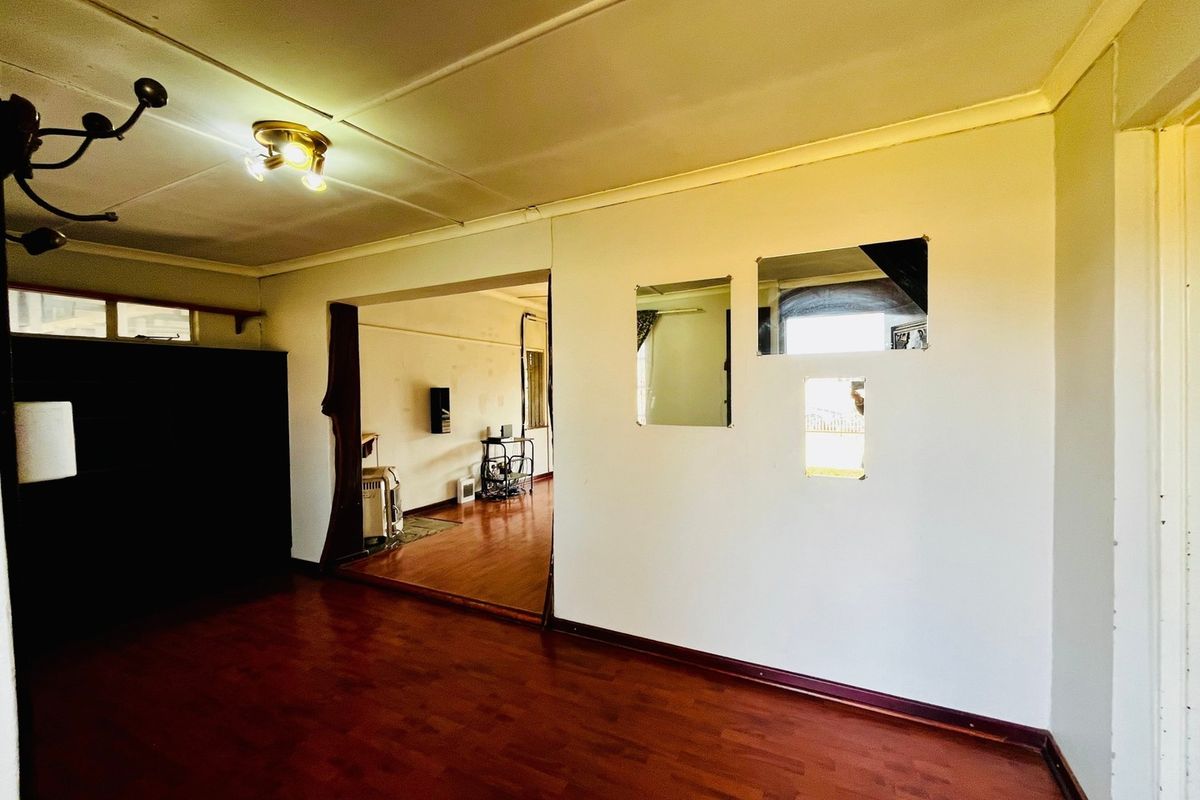 An empty living room featuring laminate flooring, ceiling coving, and unique wall cutouts, offering a blank canvas for renovation and interior design.