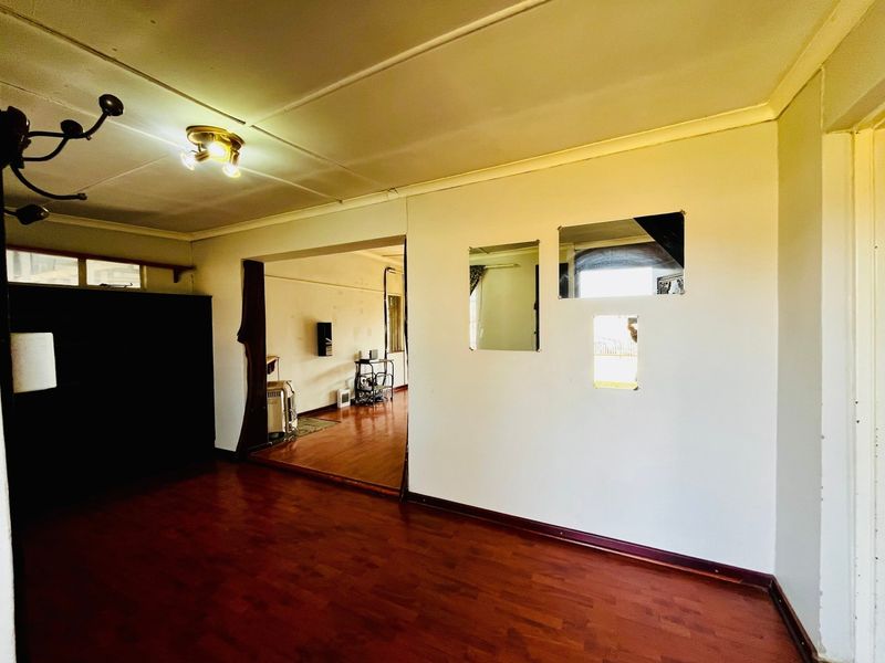 An empty living room featuring laminate flooring, ceiling coving, and unique wall cutouts, offering a blank canvas for renovation and interior design.