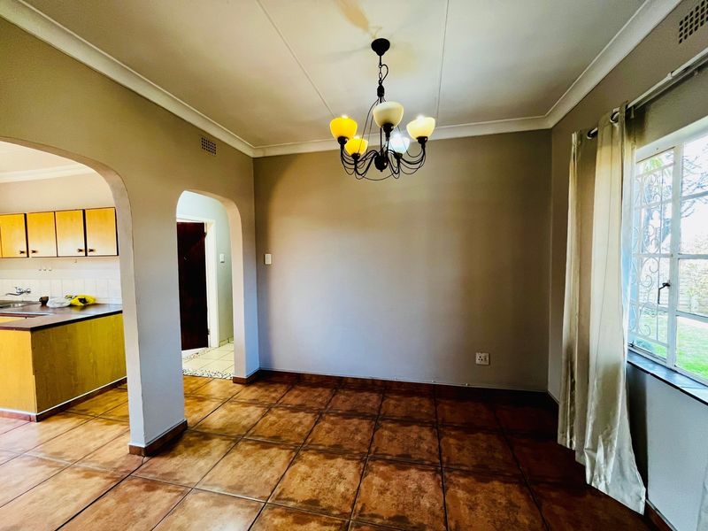 Open plan living and dining area featuring ceramic tile flooring, coved ceilings, and an arched transition to the adjacent kitchen space.