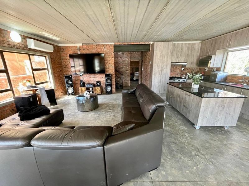 Spacious open-plan living area featuring exposed brick walls, polished concrete floors, and a modern kitchen with a central island and granite countertops.