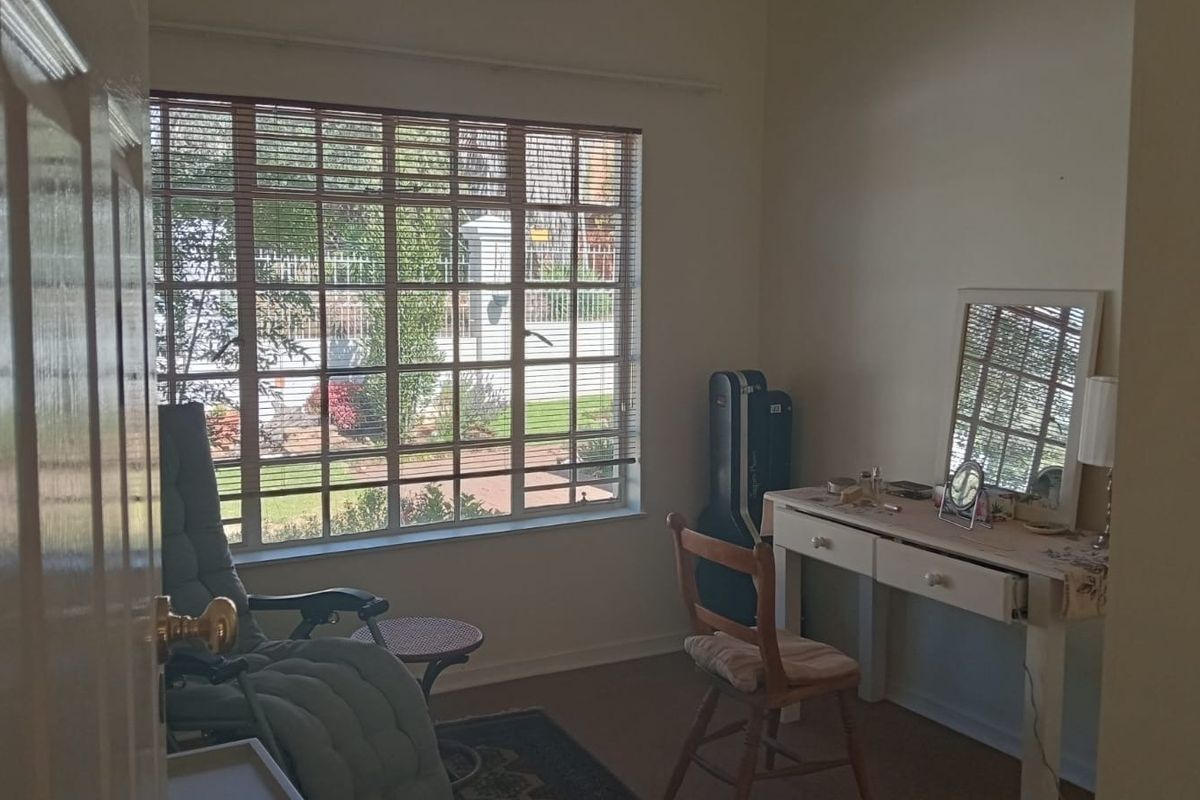 A bedroom featuring a large window with blinds, providing natural light and a view of the exterior area.