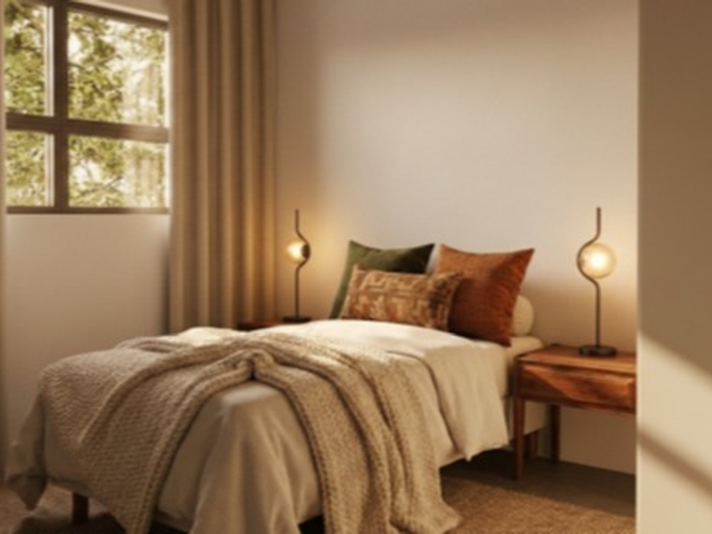 A cozy, well-lit bedroom featuring a large window that allows for natural light, creating a warm and inviting atmosphere.