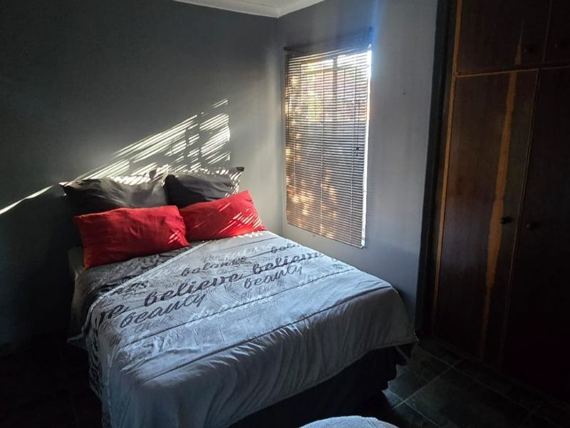 A bedroom featuring built-in wooden cupboards and venetian blinds, providing functional storage and adjustable natural light.