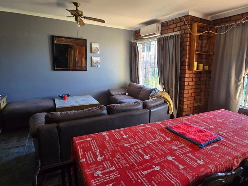 Open-plan living and dining area featuring tiled floors, an exposed brick feature wall, and a split-system air conditioner.